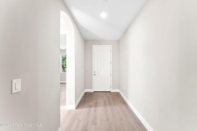 hall with vaulted ceiling and light wood-type flooring