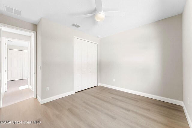 unfurnished bedroom with ceiling fan, a closet, and light hardwood / wood-style flooring