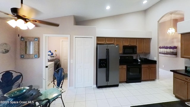 kitchen with decorative light fixtures, lofted ceiling, light tile patterned floors, black appliances, and washer and clothes dryer