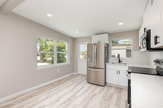 kitchen with white cabinets, stainless steel appliances, lofted ceiling, and sink