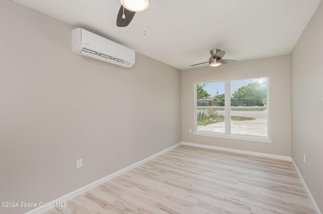 unfurnished room featuring a wall mounted air conditioner, ceiling fan, and light hardwood / wood-style floors