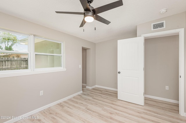 unfurnished bedroom with ceiling fan, a textured ceiling, and light hardwood / wood-style flooring