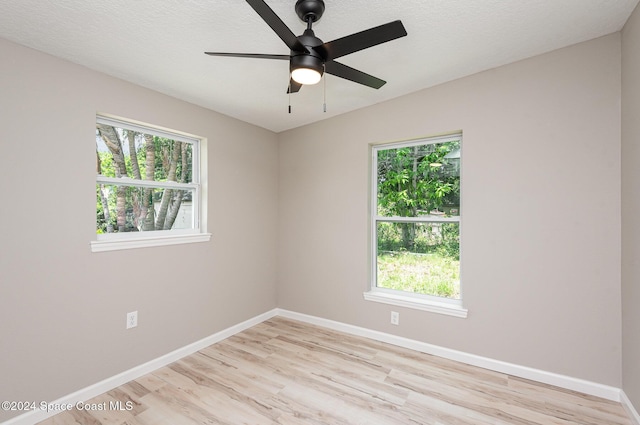 empty room with ceiling fan, light wood-type flooring, and a textured ceiling