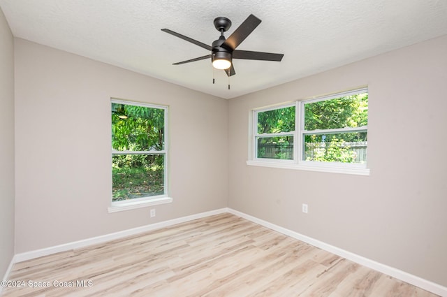 empty room with a textured ceiling, light hardwood / wood-style flooring, ceiling fan, and a healthy amount of sunlight