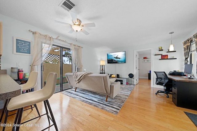 living room with ceiling fan, hardwood / wood-style floors, and a textured ceiling