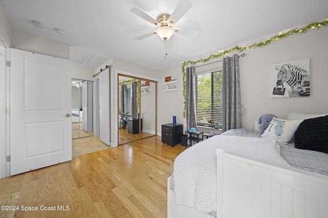 bedroom featuring ceiling fan, light hardwood / wood-style floors, and a textured ceiling