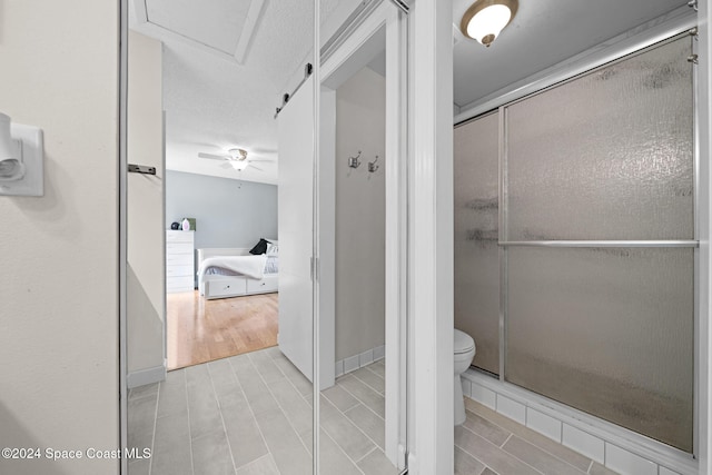 bathroom featuring hardwood / wood-style floors, toilet, an enclosed shower, and ceiling fan