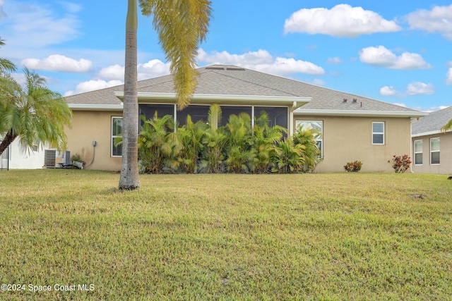 rear view of property featuring a sunroom, central air condition unit, and a lawn