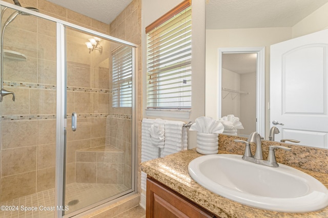 bathroom with vanity, a textured ceiling, and walk in shower