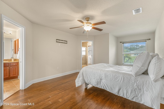 bedroom with ensuite bath, ceiling fan, a textured ceiling, and hardwood / wood-style flooring