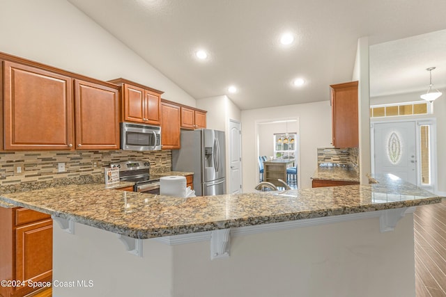 kitchen featuring a kitchen bar, kitchen peninsula, lofted ceiling, and appliances with stainless steel finishes