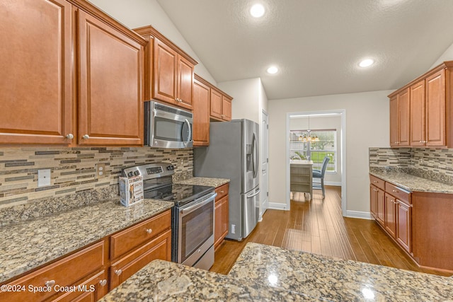 kitchen featuring backsplash, stainless steel appliances, an inviting chandelier, light hardwood / wood-style flooring, and lofted ceiling