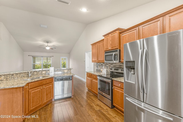 kitchen featuring light stone countertops, sink, stainless steel appliances, dark hardwood / wood-style flooring, and lofted ceiling