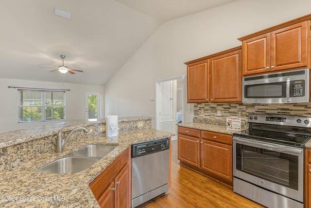 kitchen with stainless steel appliances, light hardwood / wood-style floors, lofted ceiling, and sink