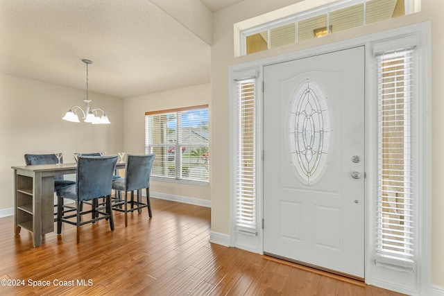 entrance foyer with hardwood / wood-style floors, a textured ceiling, and a notable chandelier