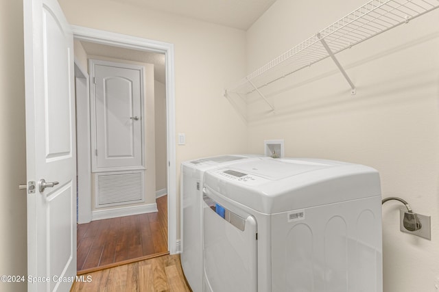 clothes washing area featuring separate washer and dryer and hardwood / wood-style floors