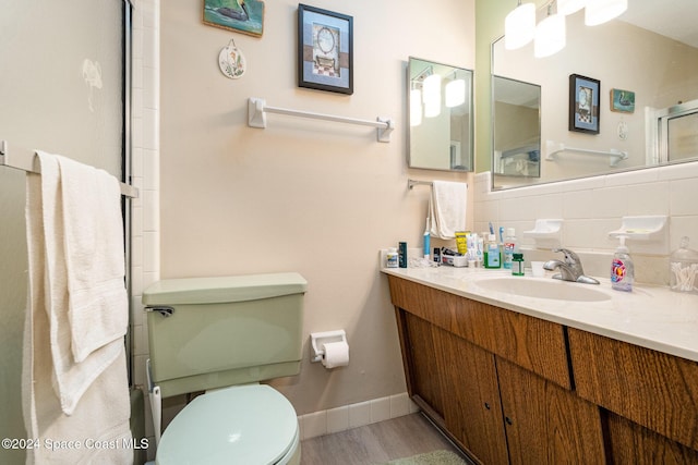 bathroom with toilet, vanity, a shower with door, hardwood / wood-style flooring, and decorative backsplash