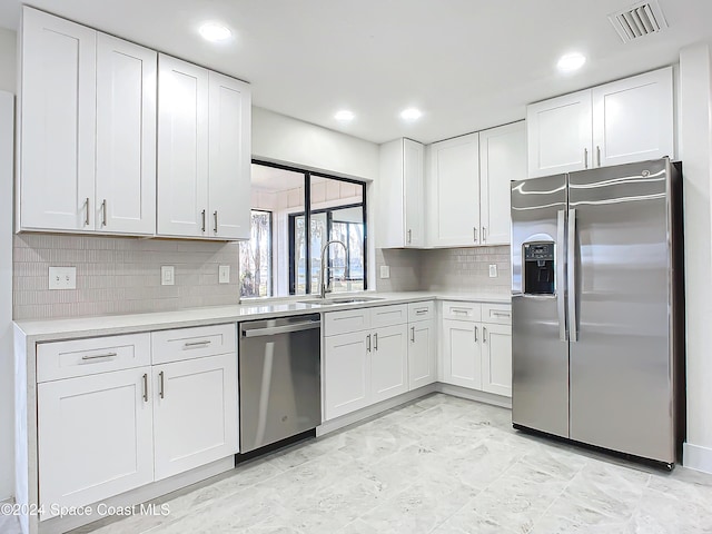 kitchen with appliances with stainless steel finishes, backsplash, white cabinetry, and sink