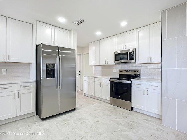 kitchen featuring tasteful backsplash, white cabinets, and stainless steel appliances