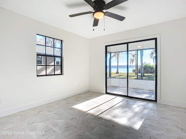 unfurnished room with ceiling fan and a water view