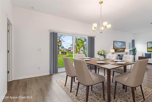 dining space with hardwood / wood-style flooring and a notable chandelier