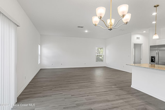 unfurnished living room featuring dark hardwood / wood-style floors and a notable chandelier