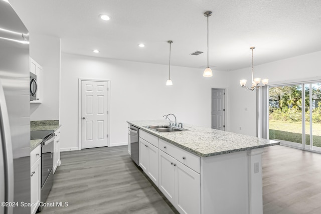 kitchen featuring stainless steel appliances, a kitchen island with sink, sink, white cabinetry, and hanging light fixtures