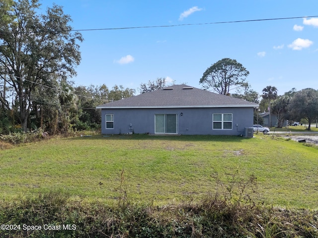 rear view of property with cooling unit and a yard