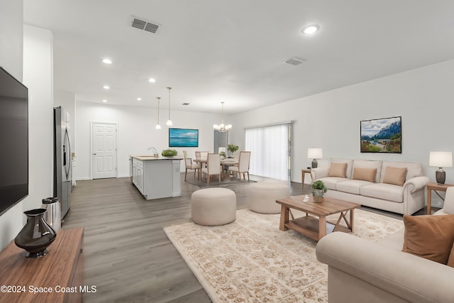 living room featuring hardwood / wood-style flooring, sink, and a chandelier