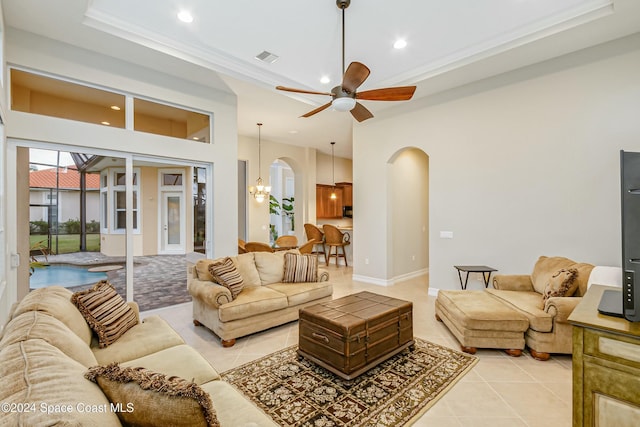 tiled living room featuring ceiling fan with notable chandelier and crown molding