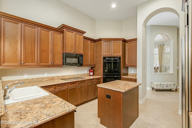 kitchen featuring sink, a kitchen island, black appliances, and light tile patterned floors