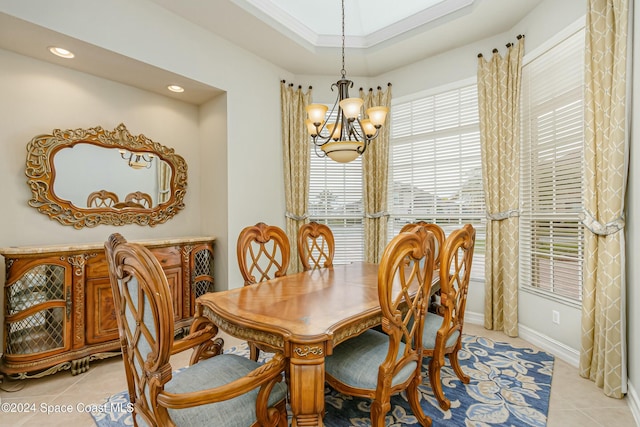 dining area featuring a notable chandelier, a raised ceiling, light tile patterned floors, and ornamental molding