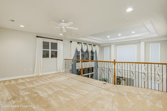 empty room featuring ceiling fan and a raised ceiling