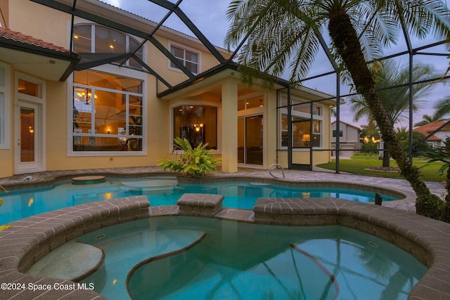 pool at dusk with glass enclosure, an in ground hot tub, and a patio