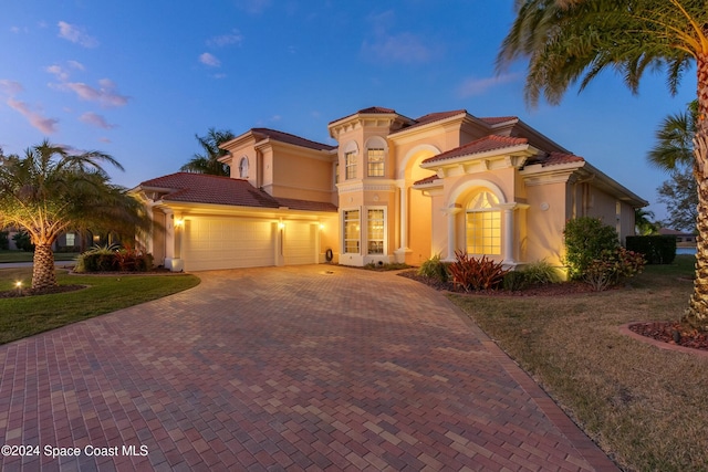 mediterranean / spanish house featuring a lawn and a garage