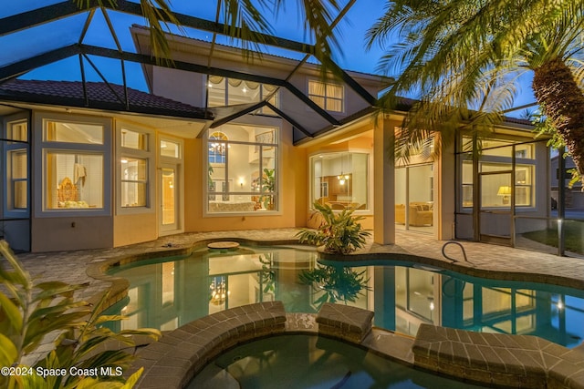 back of house with a lanai, a patio, and a pool with hot tub