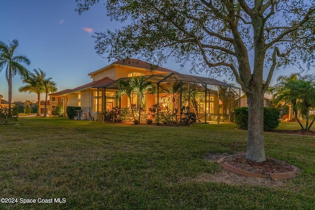 exterior space with glass enclosure and a lawn