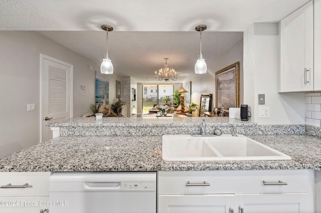 kitchen featuring light stone counters, a peninsula, white dishwasher, a sink, and white cabinetry