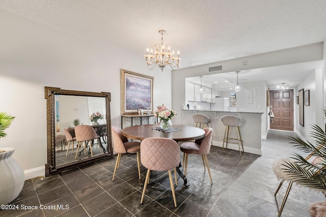 dining room featuring visible vents, baseboards, a textured ceiling, and a chandelier