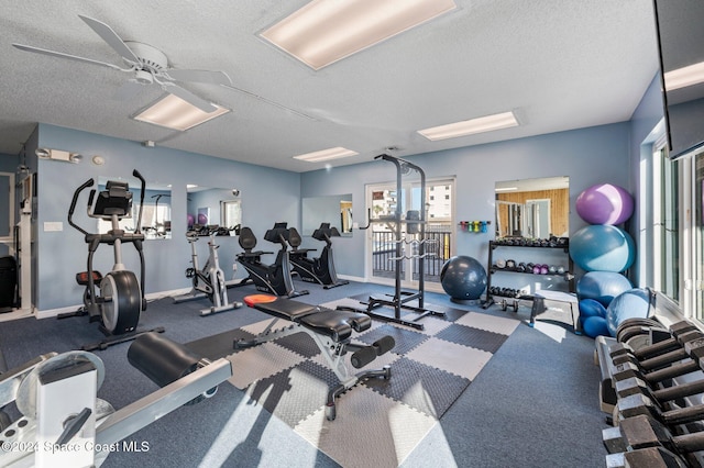 workout area featuring baseboards, a textured ceiling, and a ceiling fan