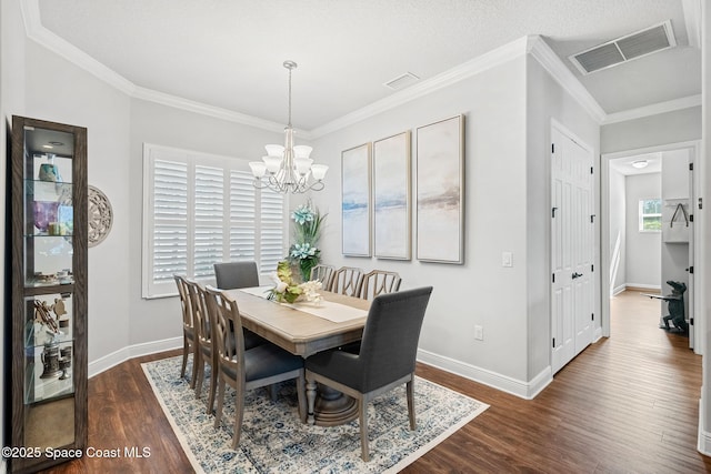 dining area with a textured ceiling, dark wood-type flooring, crown molding, and a notable chandelier