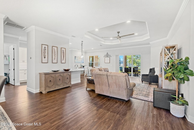 living room featuring dark hardwood / wood-style floors, a raised ceiling, ceiling fan, and crown molding