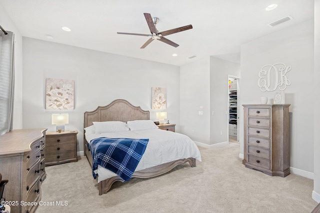 bedroom with ceiling fan, light colored carpet, a walk in closet, and a closet