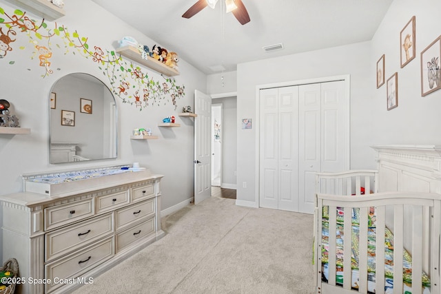 carpeted bedroom featuring ceiling fan, a crib, and a closet