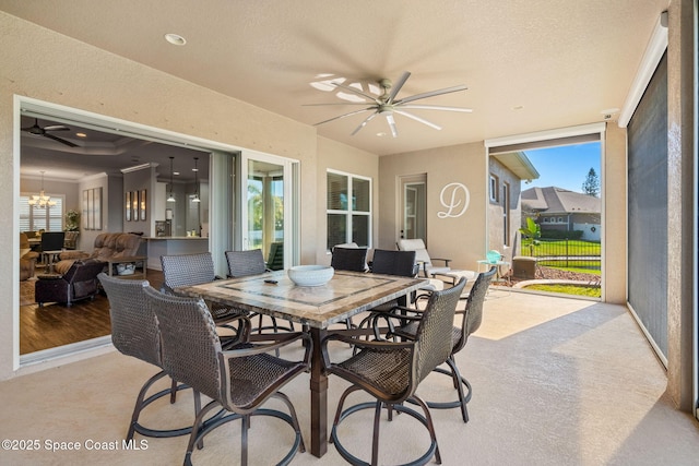 sunroom / solarium featuring a healthy amount of sunlight and ceiling fan with notable chandelier