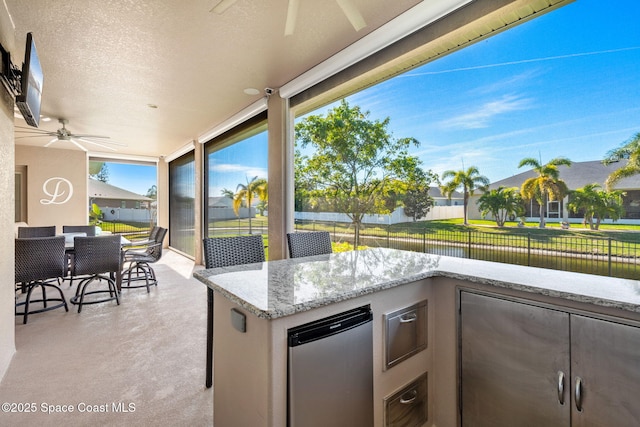 view of patio / terrace featuring ceiling fan, a water view, and exterior bar