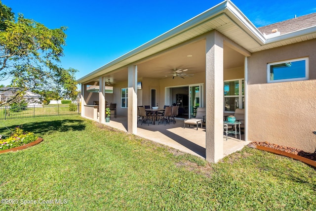 rear view of property with area for grilling, ceiling fan, a patio area, and a lawn