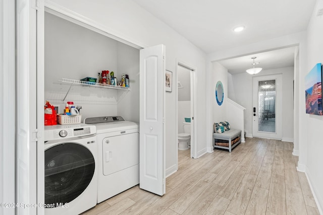 washroom with light hardwood / wood-style flooring and washing machine and clothes dryer