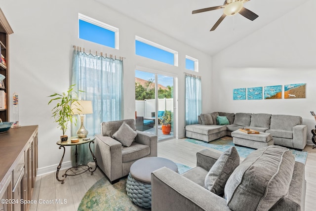 living room featuring ceiling fan, light hardwood / wood-style floors, and a high ceiling