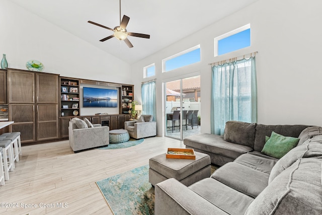 living room with ceiling fan, a high ceiling, and light wood-type flooring